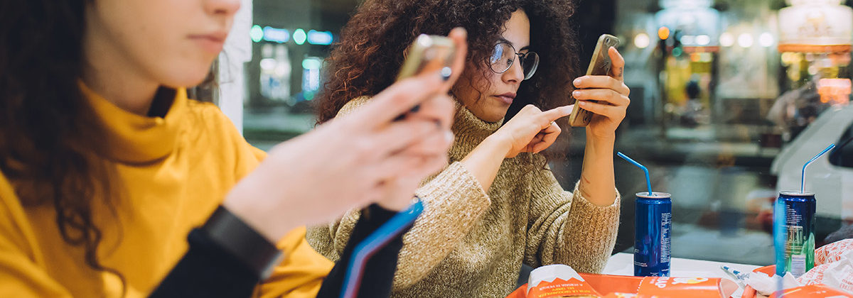 millennials on mobile phone at eating fast food at QSR