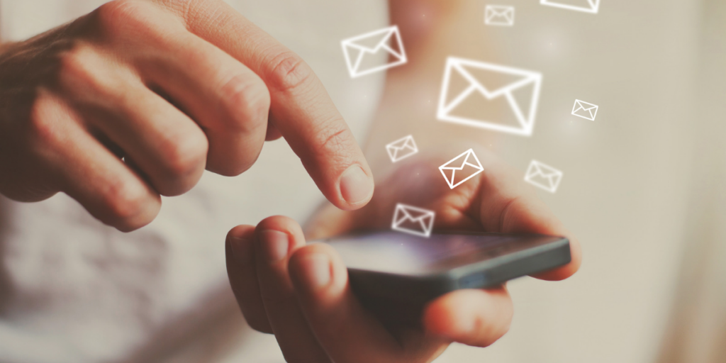 Hands holding a cellphone with icons of emails (envelopes).