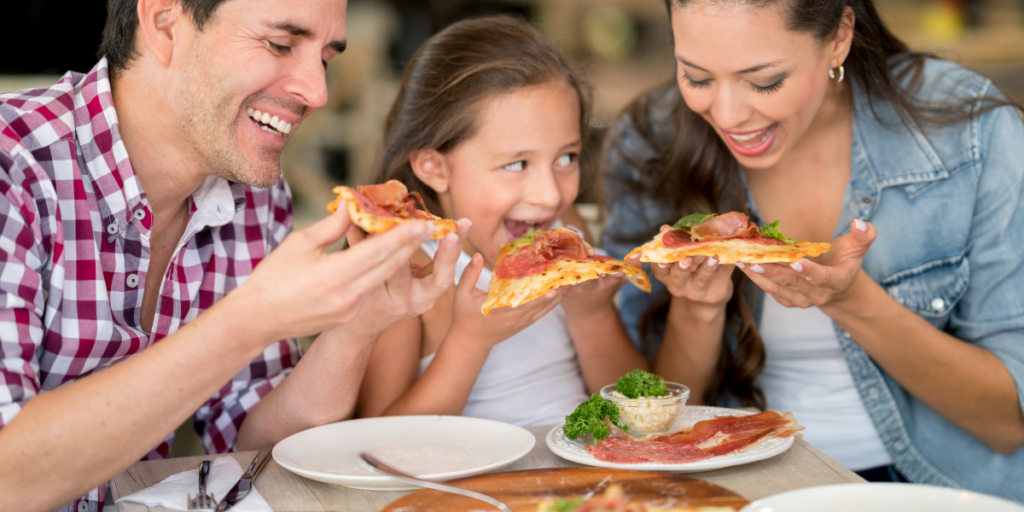 A man, child, and woman (a family) eat pizza together.