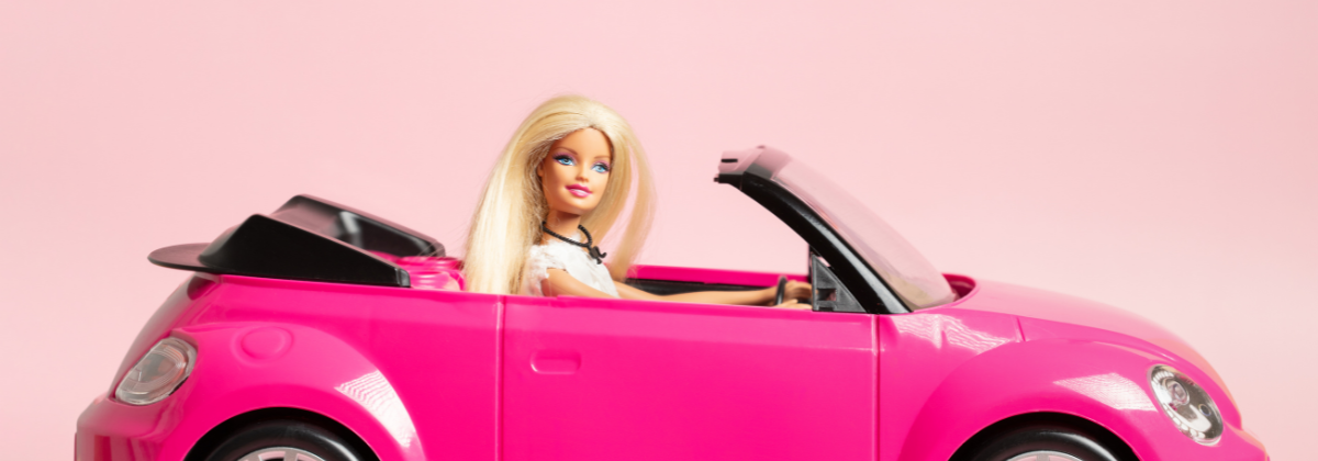 A blonde Barbie doll driving a toy, pink convertible.