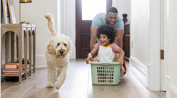 Child and parent play on floor with dog